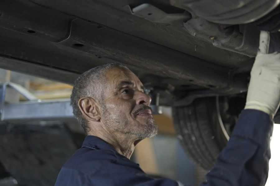 Mechanic inspecting the underside of a car